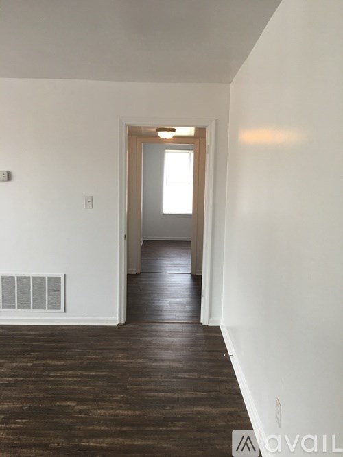 A hallway with wood flooring and white walls.