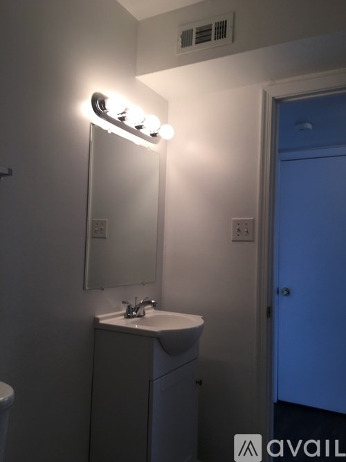 A bathroom with a sink, mirror, and light fixture.