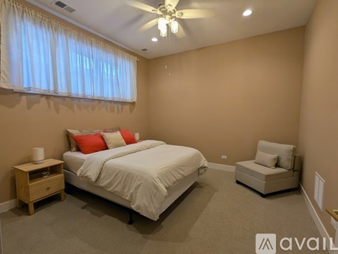 A bedroom with a bed, chair, and window with curtains.