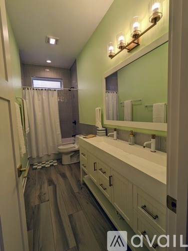A bathroom with a toilet, sink, and mirror.