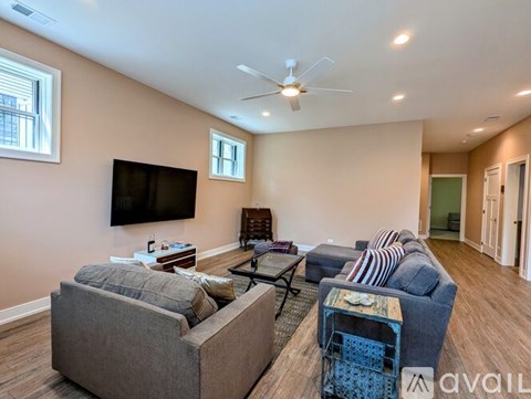 A living room with a grey couch, a black TV, and a wooden chair.