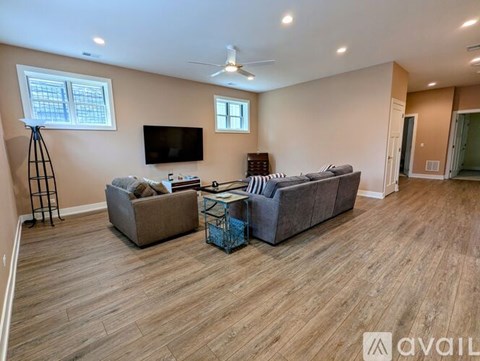A living room with a grey couch, a black TV, and a wooden floor.
