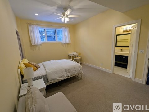 A bedroom with a bed, nightstand, and a window with white curtains.