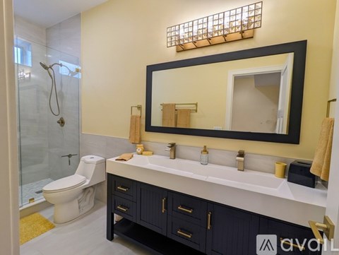 A bathroom with a white toilet, a sink with a mirror above it, and a shower with a glass door.