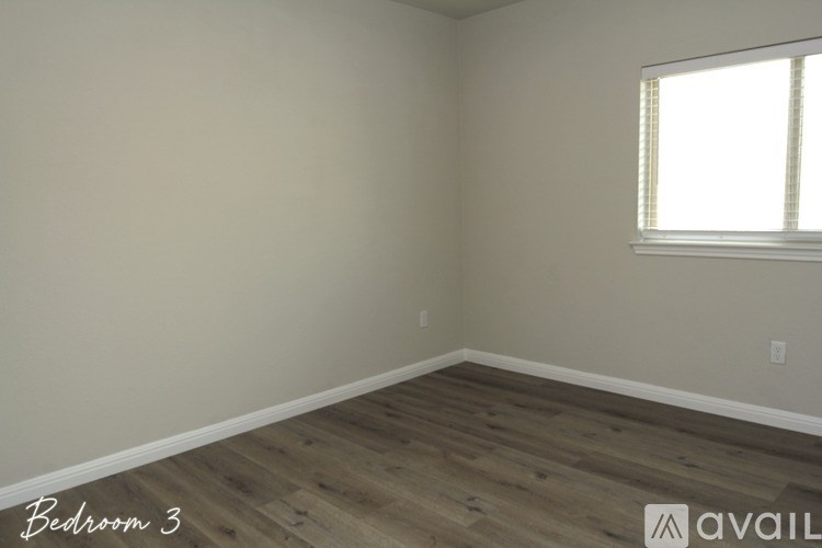 A room with wooden flooring and a window with blinds.