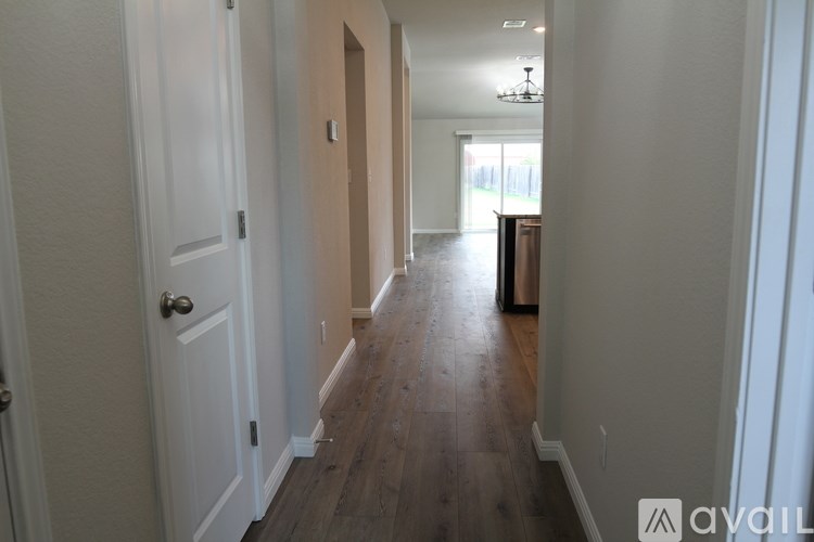 A long hallway with wood floors and white walls.