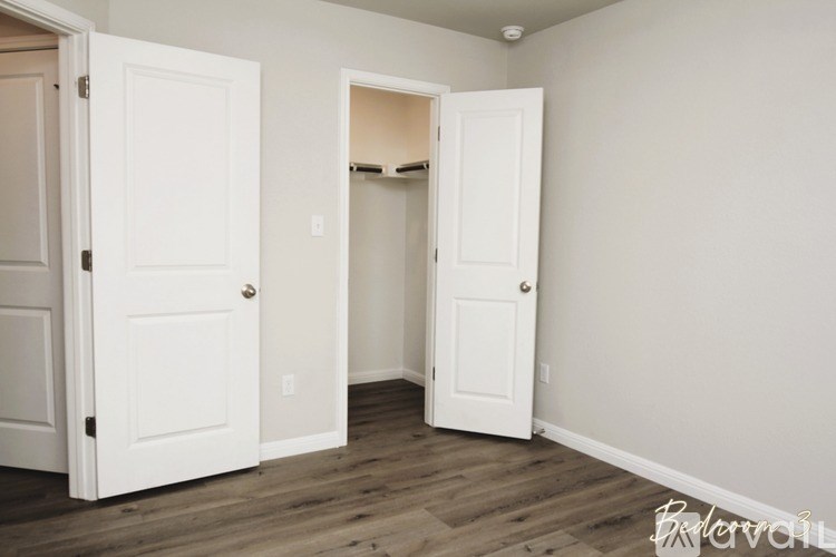 A room with two white doors and a wooden floor.