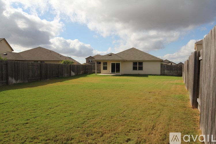 A backyard with a wooden fence and a house in the background.