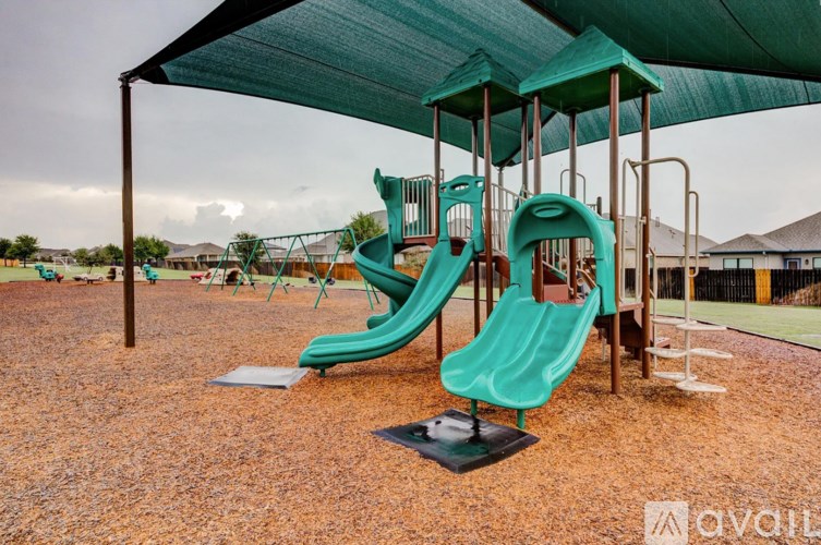 A playground with a green slide and a green canopy.