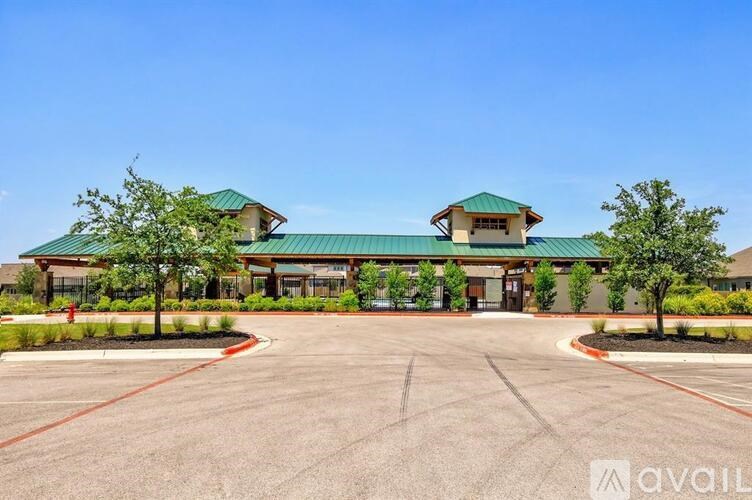 A large building with a green roof and a parking lot in front.
