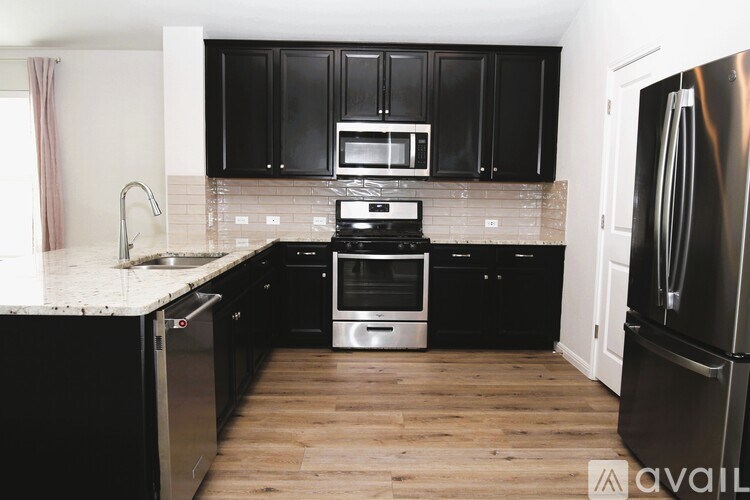 A kitchen with black cabinets and stainless steel appliances.