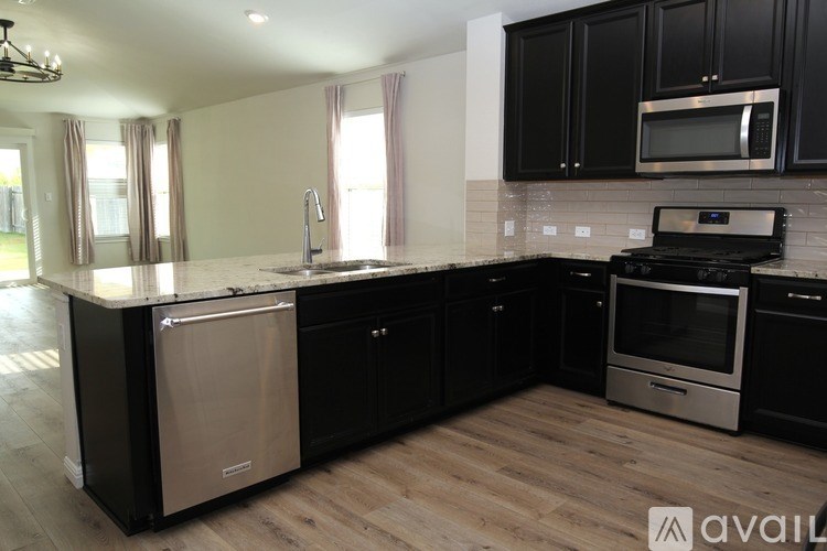 A kitchen with black cabinets and a wooden floor.