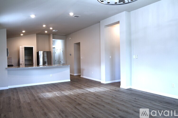 A spacious room with wooden flooring and a bar area.
