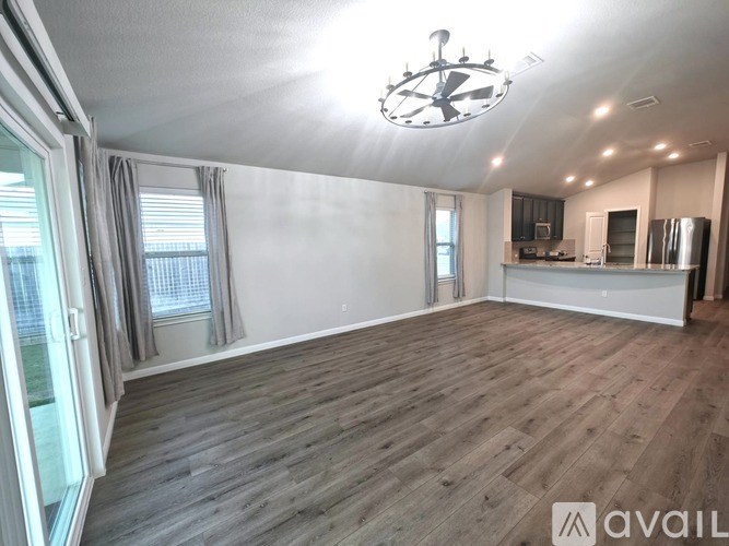 A spacious room with wooden flooring and a chandelier hanging from the ceiling.