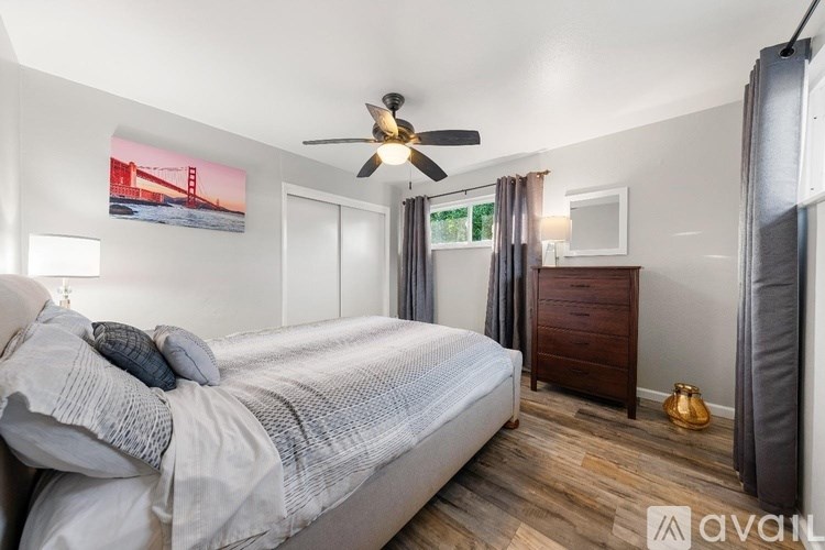 A bedroom with a bed, dresser, and a ceiling fan.