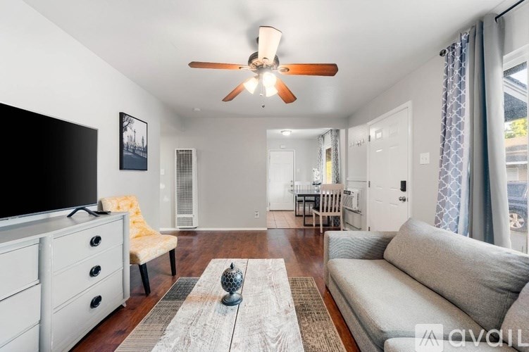 A living room with a grey couch, a white cabinet, a television, and a rug.