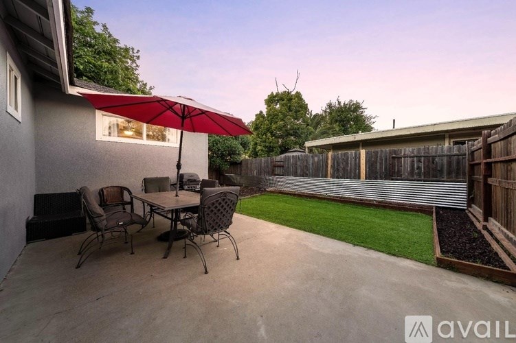 A patio with a table and chairs under an umbrella.
