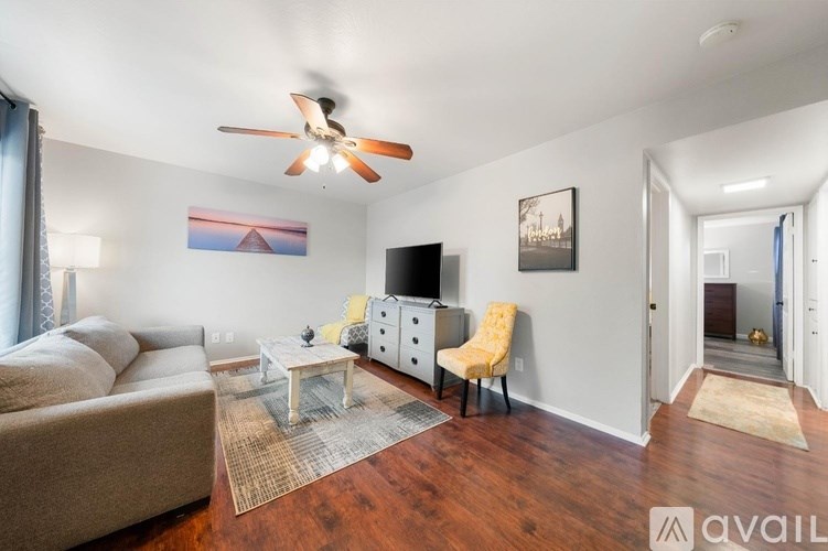 A living room with a brown couch, a white coffee table, and a ceiling fan.