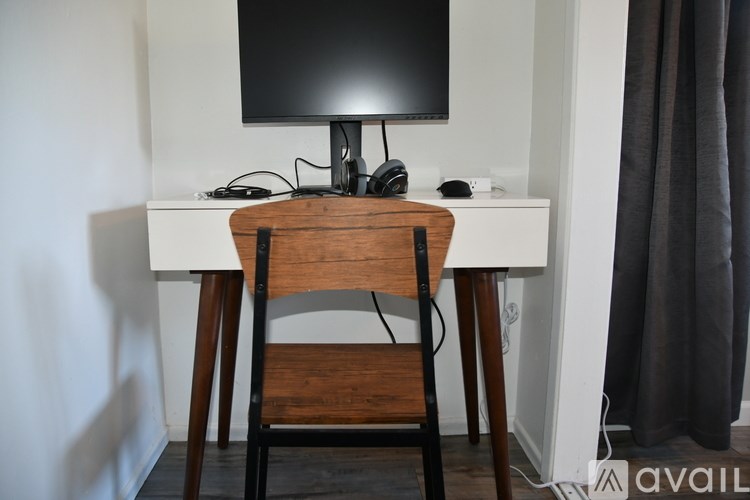 A computer desk with a monitor, keyboard, mouse and headphones.