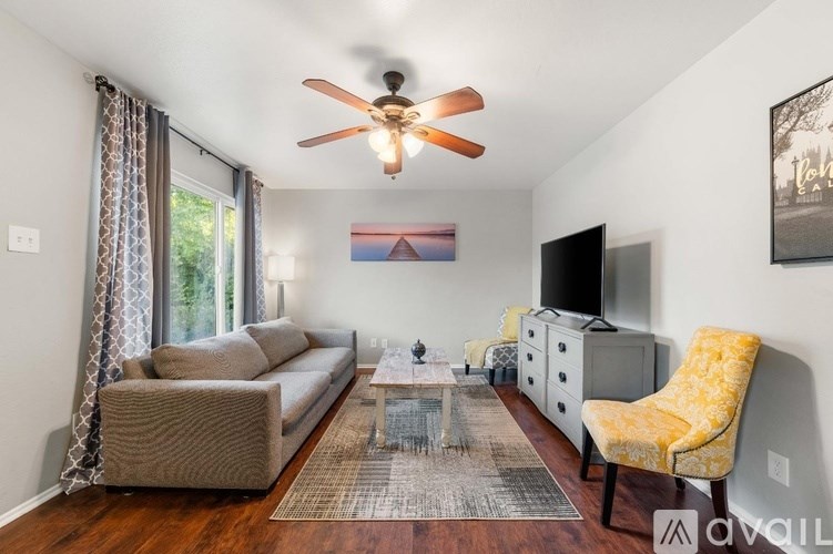 A living room with a brown couch, a yellow chair, and a ceiling fan.