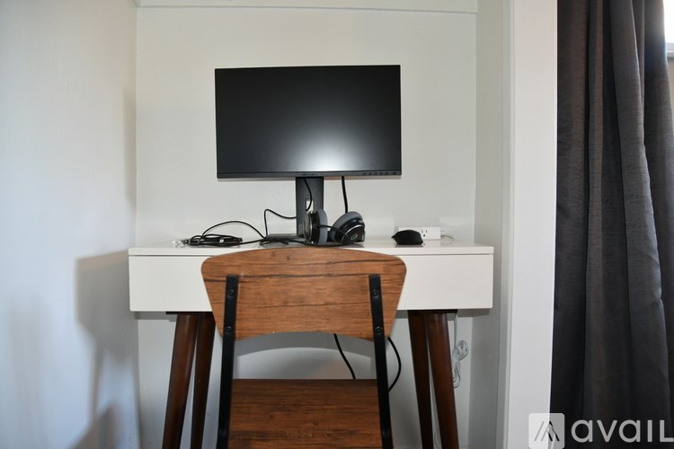 A black monitor sits on a wooden desk with a mouse and headphones.