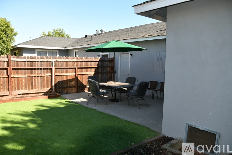 A backyard with a green lawn and a white patio table.