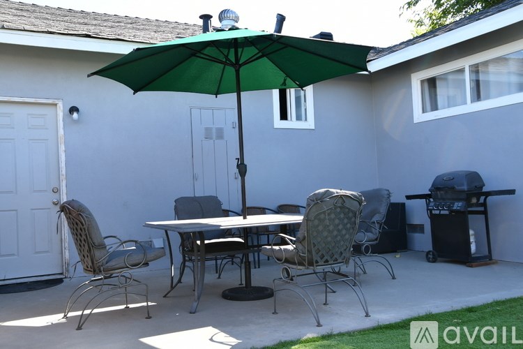 A patio with a table, chairs, and an umbrella.