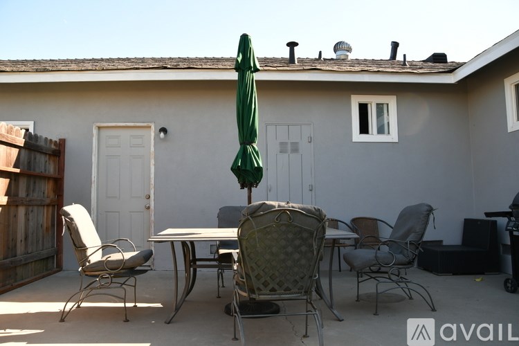 A patio with a table, chairs, and an umbrella.