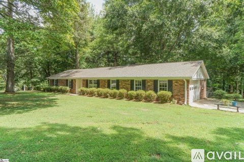 A house with a green lawn and trees in the background.