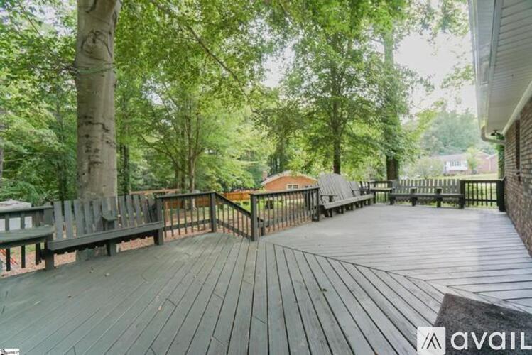A wooden deck with a railing and trees in the background.