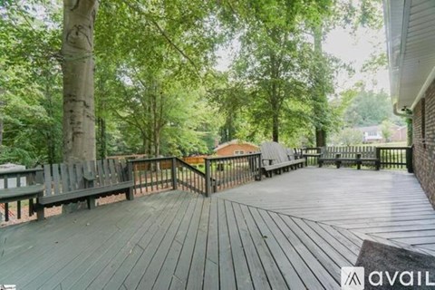 A wooden deck with a railing and trees in the background.