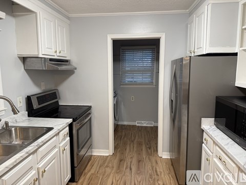 A kitchen with white cabinets and a black countertop.