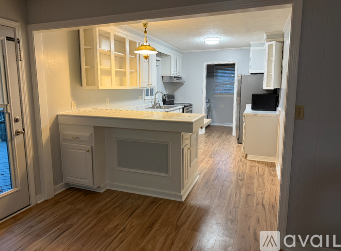 A kitchen with white cabinets and a wooden floor.