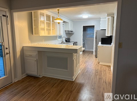 A kitchen with white cabinets and a wooden floor.
