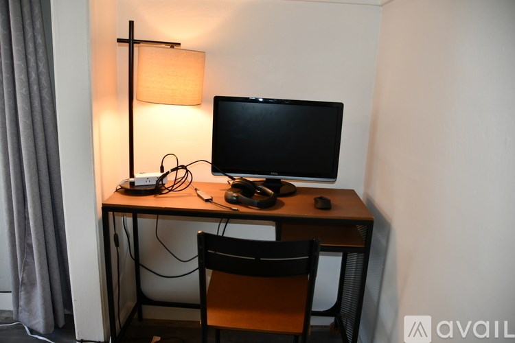 A desk with a computer monitor, keyboard, mouse, and lamp.