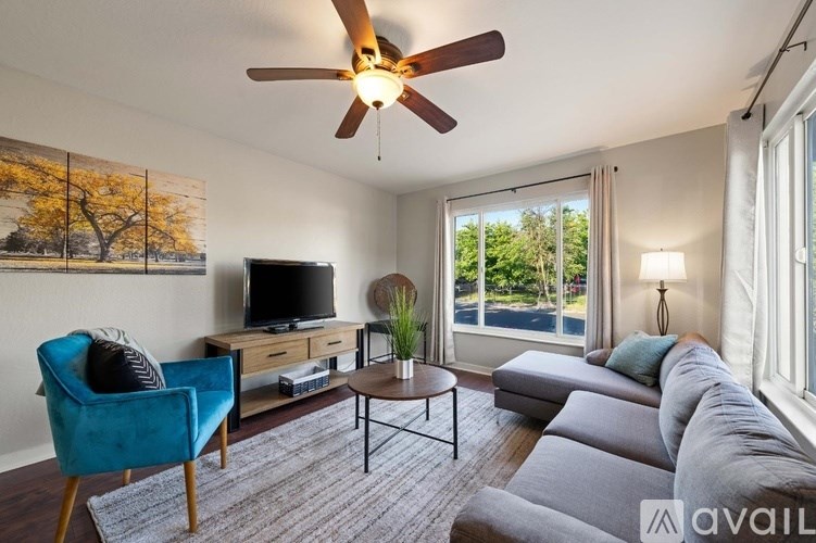 A living room with a blue chair, a television, and a ceiling fan.
