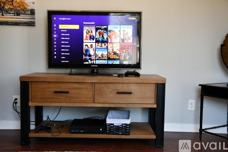 A TV on a wooden stand with a remote control and a black box underneath it.