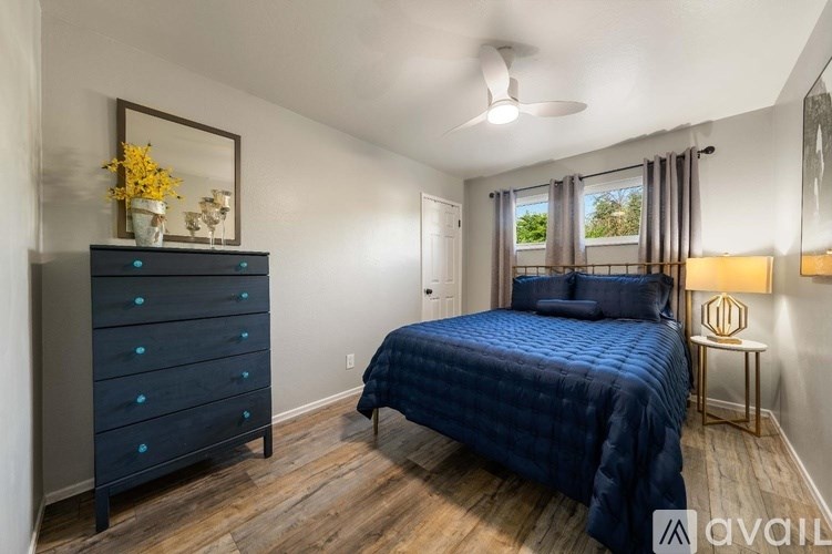 A bedroom with a blue bedspread and a wooden floor.