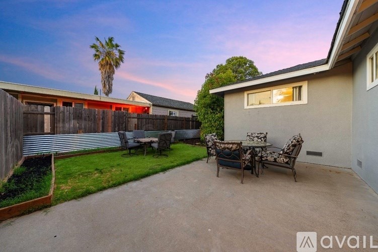A backyard with a patio table set and a palm tree.