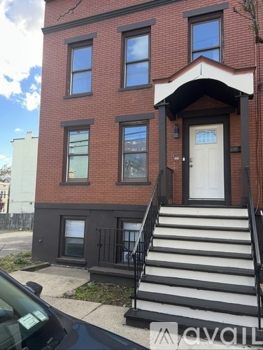 A red brick house with a white door and black railings.