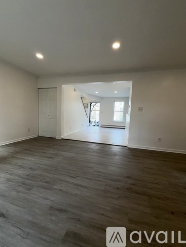 A spacious room with wooden flooring and a doorway leading to another room.