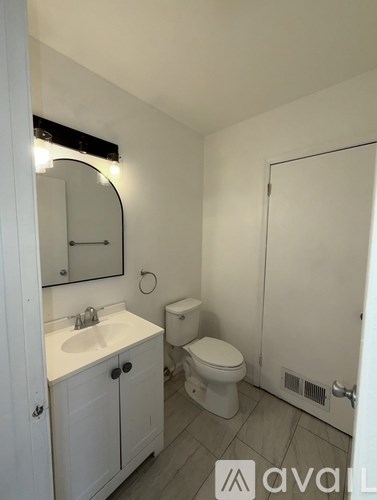 A small white bathroom with a toilet, sink, and mirror.