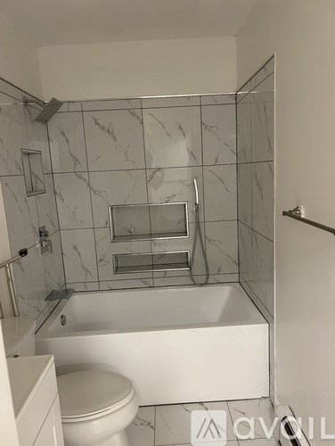 A white bathroom with a marble tile shower.