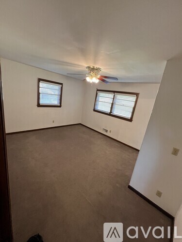 A room with a brown carpet and a ceiling fan.