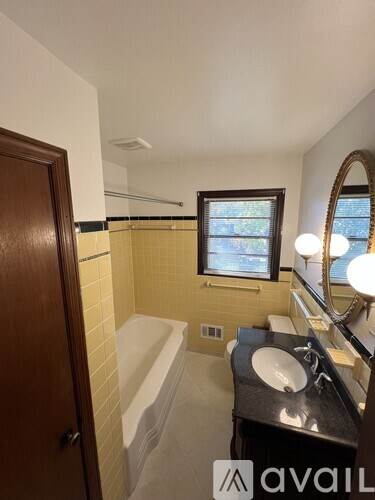 A bathroom with a tub, sink, mirror, and a window.