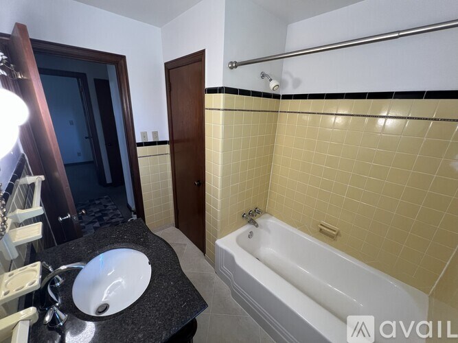 A bathroom with a sink, mirror, and bathtub.