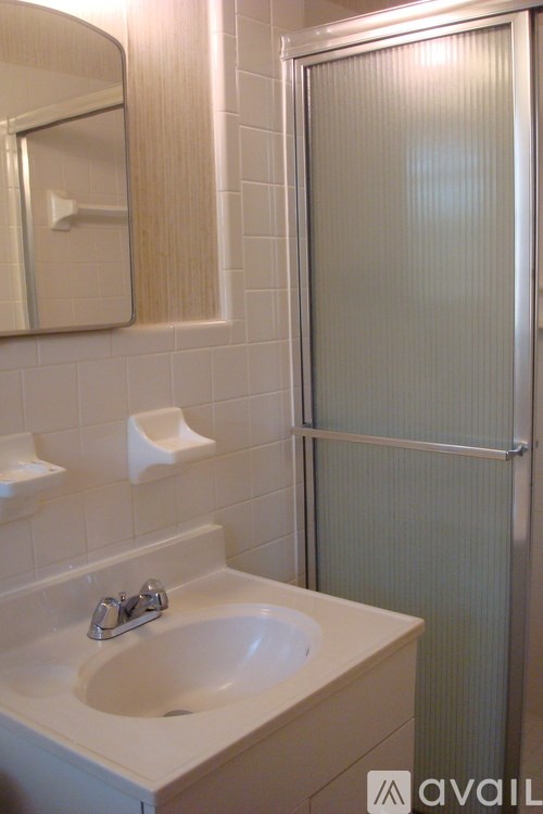 A bathroom with a sink, mirror, and shower.
