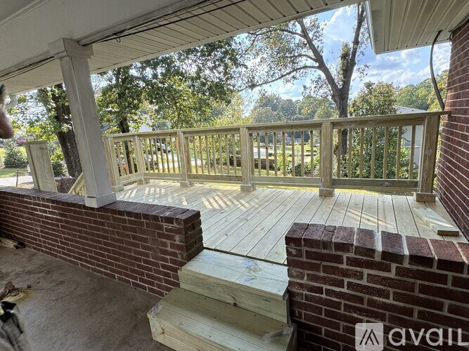 A wooden deck with a brick pillar and a white railing.