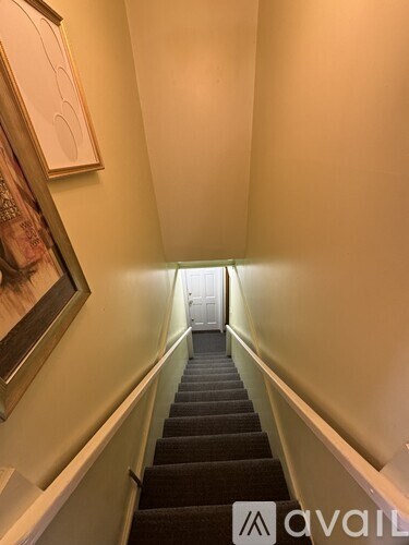 A staircase with a carpeted runner and white walls.
