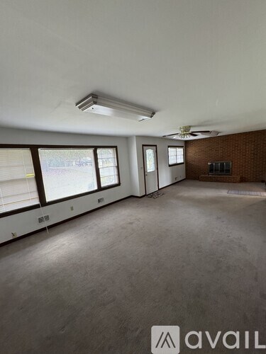 A spacious room with a fan and a window overlooking a street.